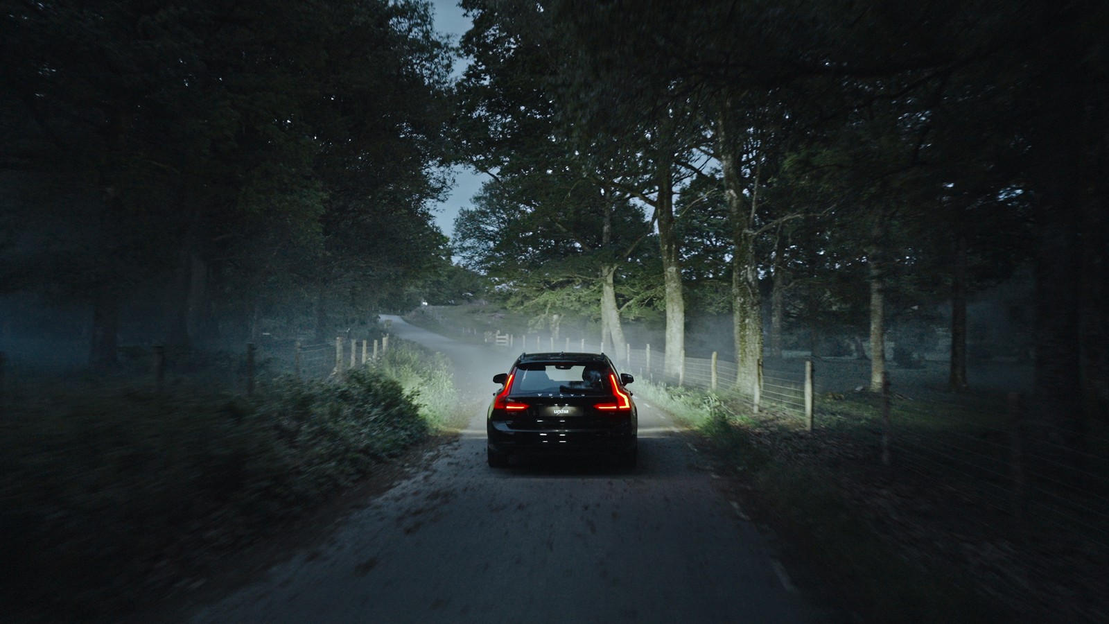 Car on a dark forest road lit by Luxtar Twilight